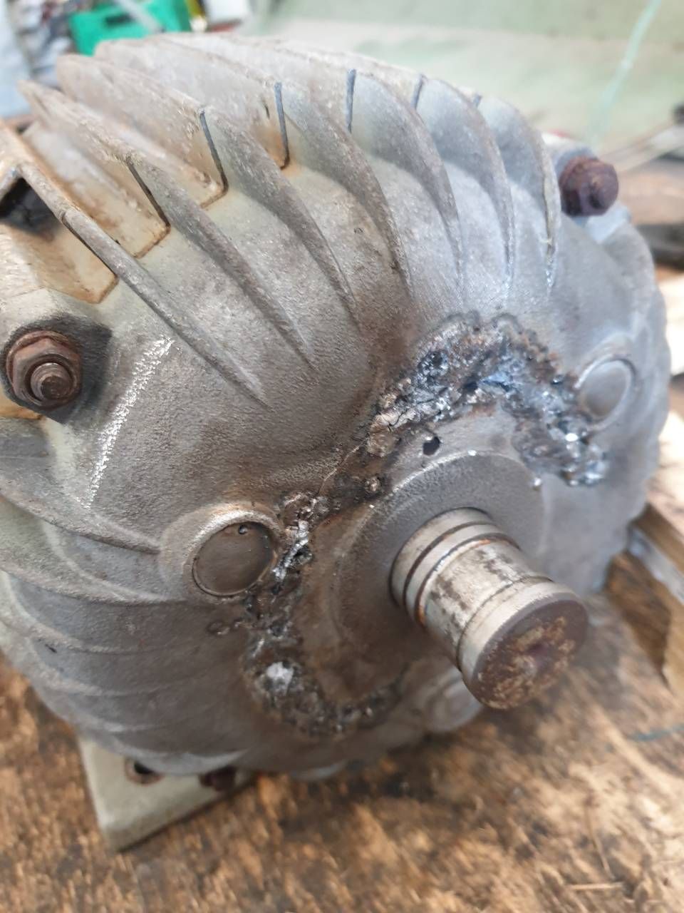 Nahaufnahme eines beschädigten grauen Elektromotors mit beschädigter Welle und verschlissenem, verrostetem Gehäuse.