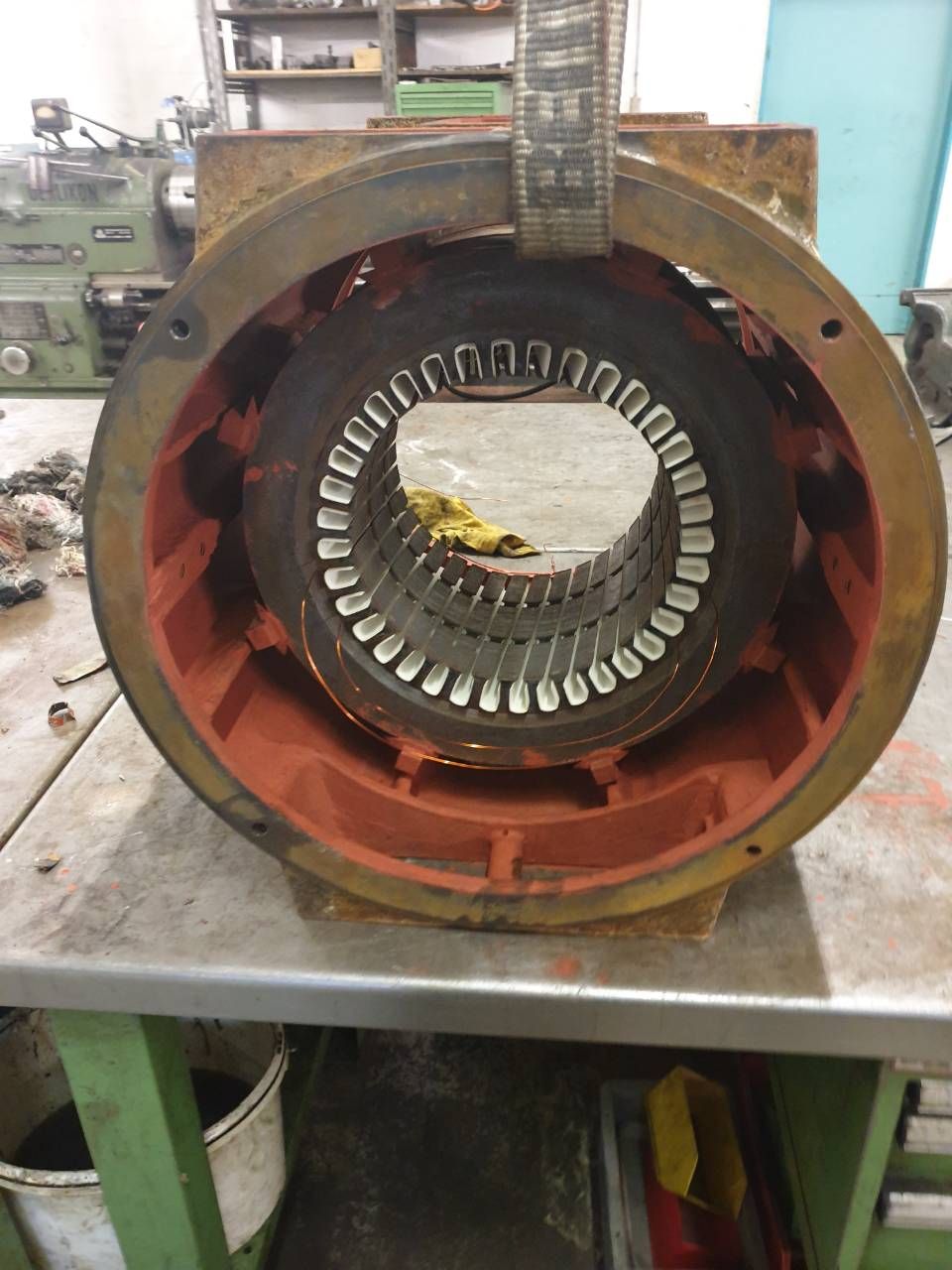 Grosses Industriemotor- oder Generatorgehäuse mit freiliegenden Statorwicklungen auf einem Werkstatttisch.