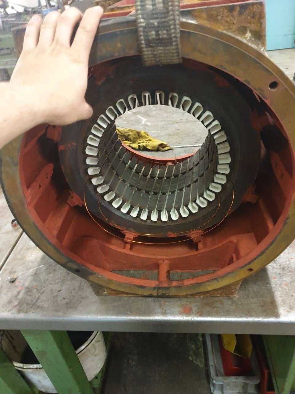 Eine Hand hält einen aufgeschnittenen Elektromotor, der die Kupferwicklungen und das rote Gehäuse zeigt.