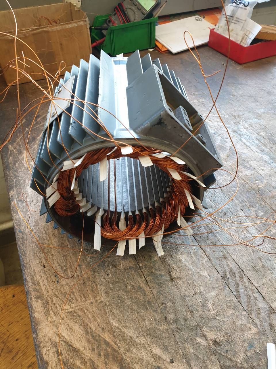 Kupfer- und grauer Elektromotorstator mit Spulen auf einer hölzernen Werkbank
