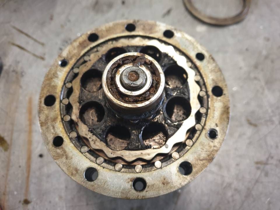 Nahaufnahme einer rostigen, mechanischen Metallzahnradbaugruppe mit kreisförmigen Bolzenlöchern.