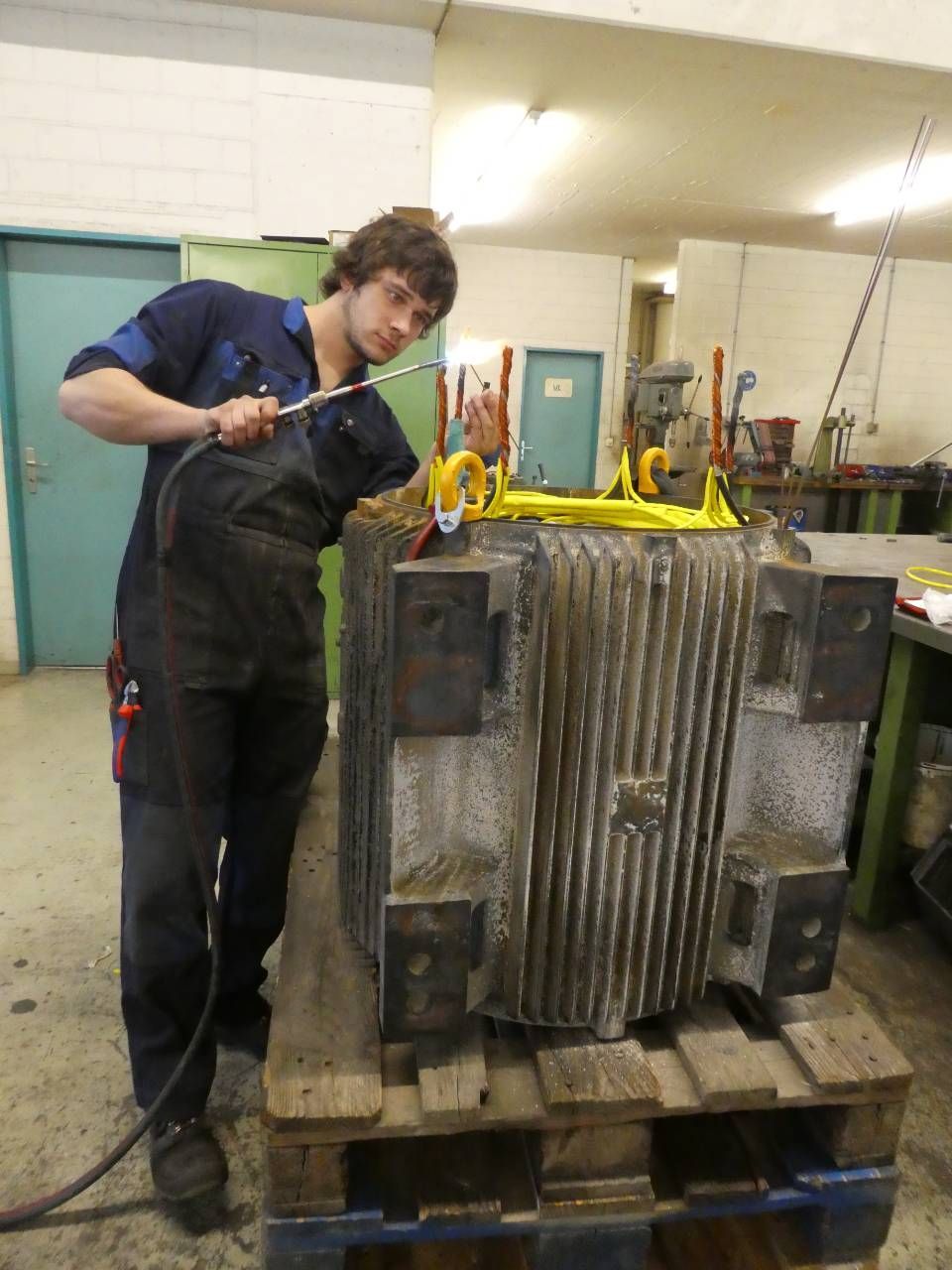 Ein Arbeiter reinigt eine grosse Metallmaschine in einer Industriewerkstatt