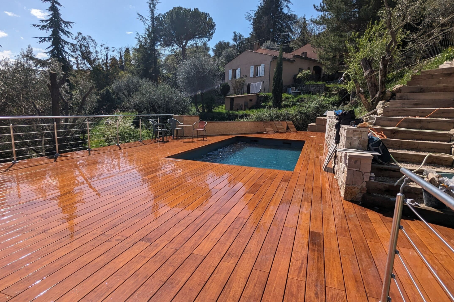 Une terrasse en bois avec une piscine en arrière-plan