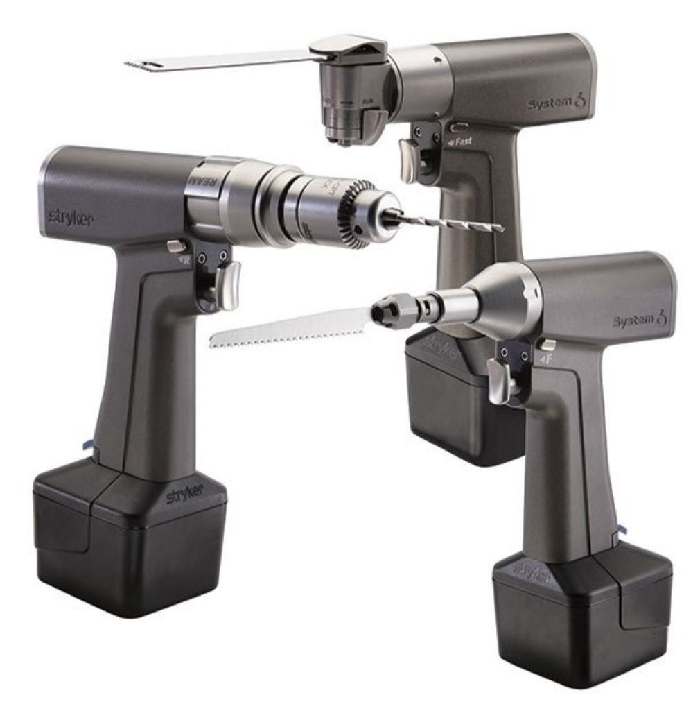 A silver surgical drill with various attachments, likely for orthopedic procedures.