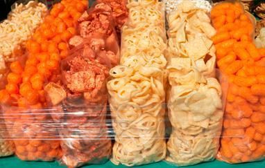 Una variedad de bocadillos en bolsas de plástico están alineados en una mesa.