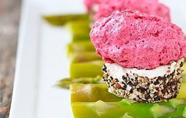 Un primer plano de un plato de comida con espárragos y una magdalena encima.