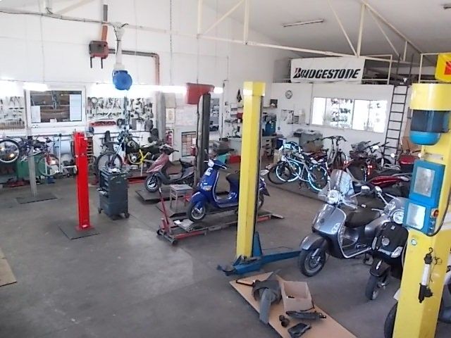 Motorradwerkstatt mit Motorrädern auf Hebebühnen und Werkzeugen in einer hellen Garage