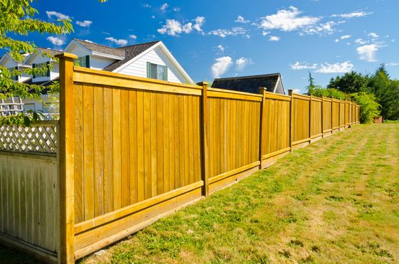 Longue clôture en bois pour préserver l'intimité d'une cour herbeuse.