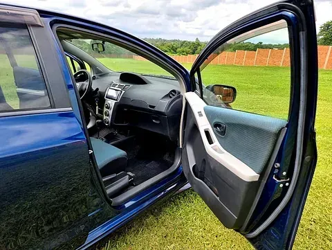 Un coche azul con las puertas abiertas está aparcado en un campo de hierba.