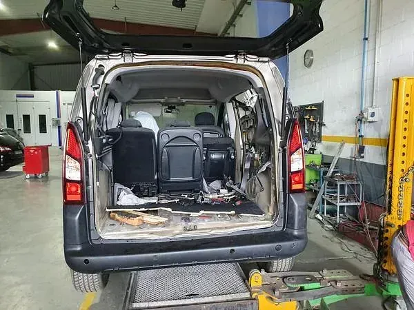 Una furgoneta está parada en un elevador en un garaje con el maletero abierto.