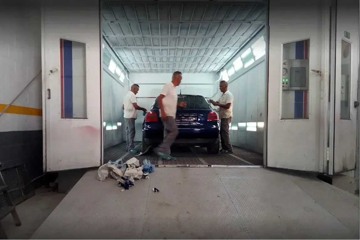 Dos hombres están pintando un coche azul en un garaje.