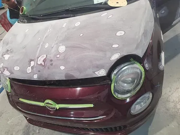 Se está pintando un coche rojo en un garaje.