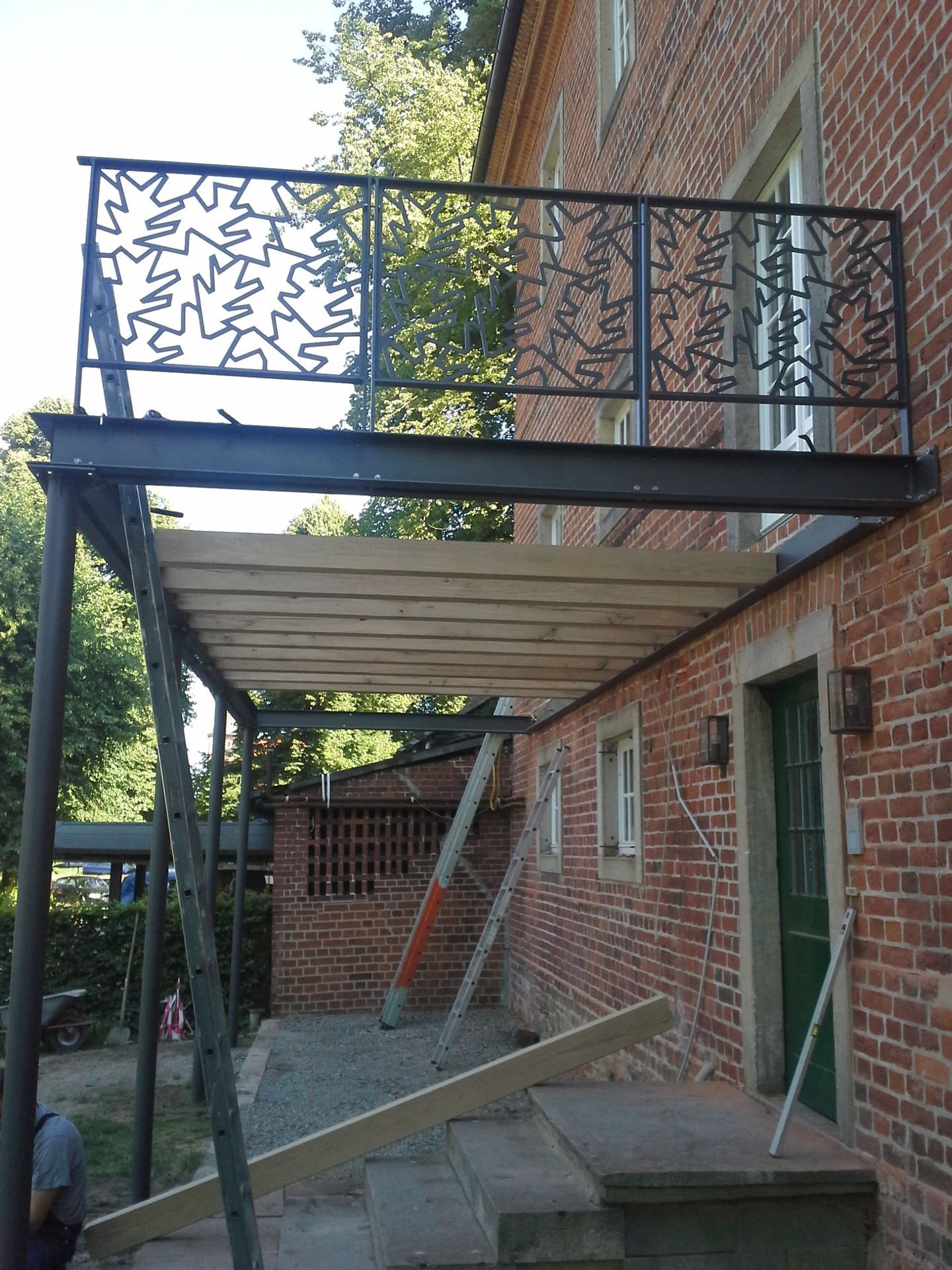 Eine Außentreppe aus Metall und ein Balkon sind an ein Backsteingebäude angebaut