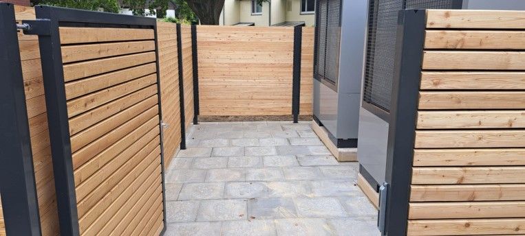 Moderner Außenweg mit grauen Pflastersteinen und Holzlattenzäunen