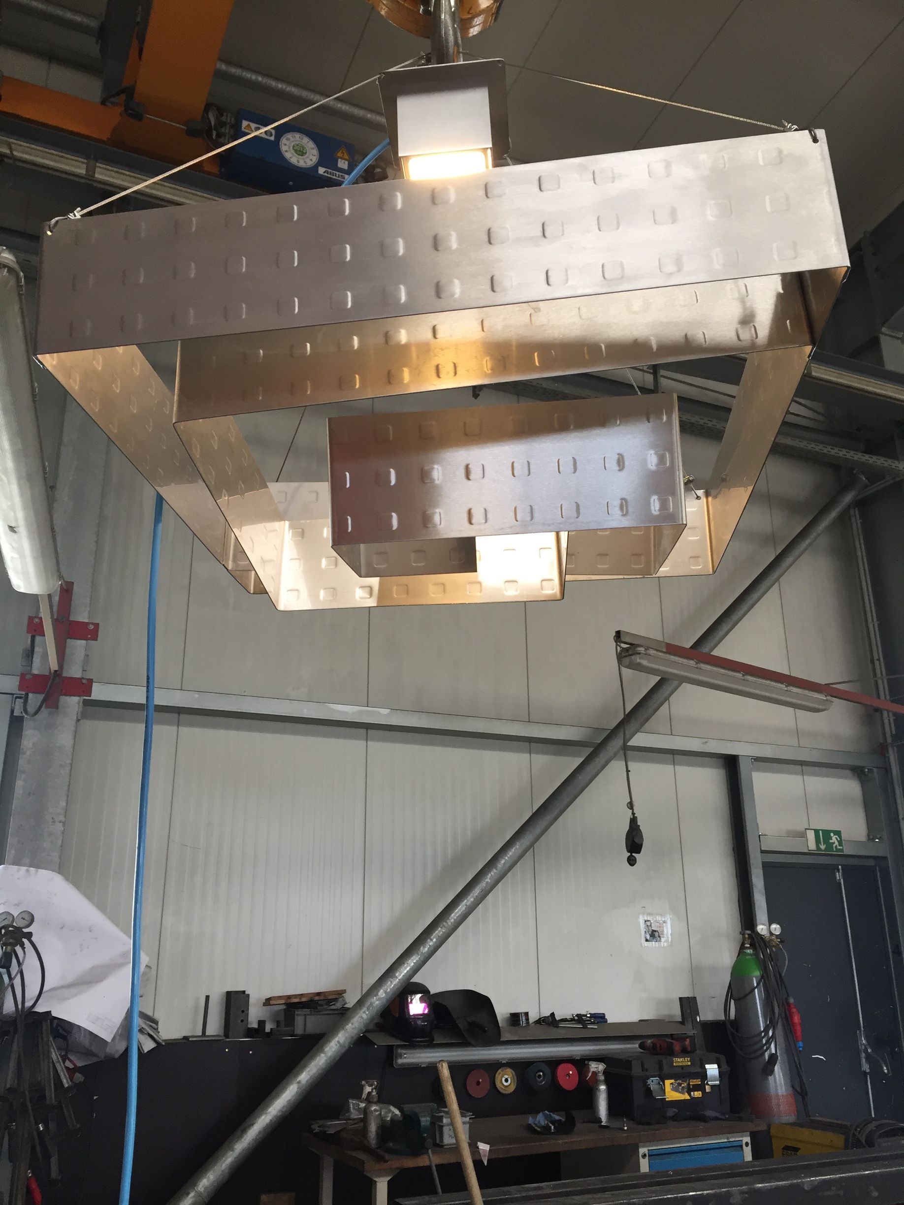 Metallische, geometrische Hängeskulptur mit Beleuchtung an der Decke einer Industriegarage