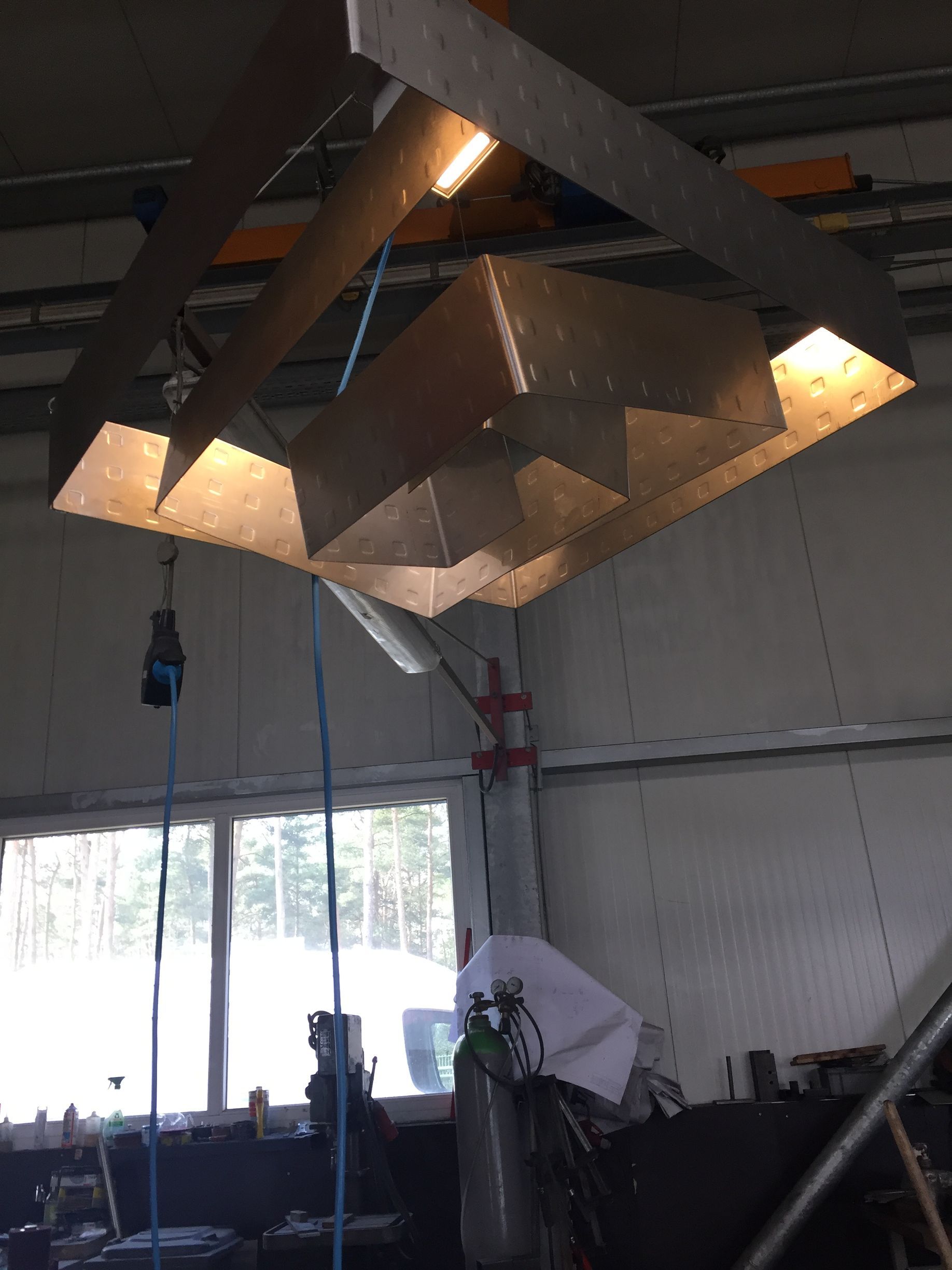 Große geometrische Metallleuchte hängt in einer Industriewerkstatt