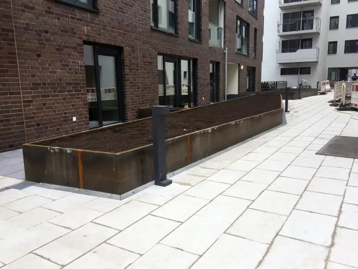 Moderner Apartmenthof mit Backsteingebäuden, Hochbeeten und einem gepflasterten Gehweg