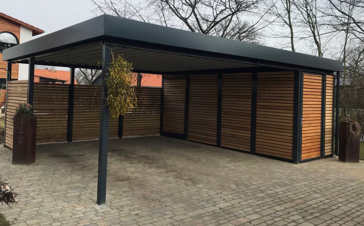 Überdachter Holzparkplatz mit schwarzen Metallstützen und Lattenwänden auf einem gepflasterten Parkplatz