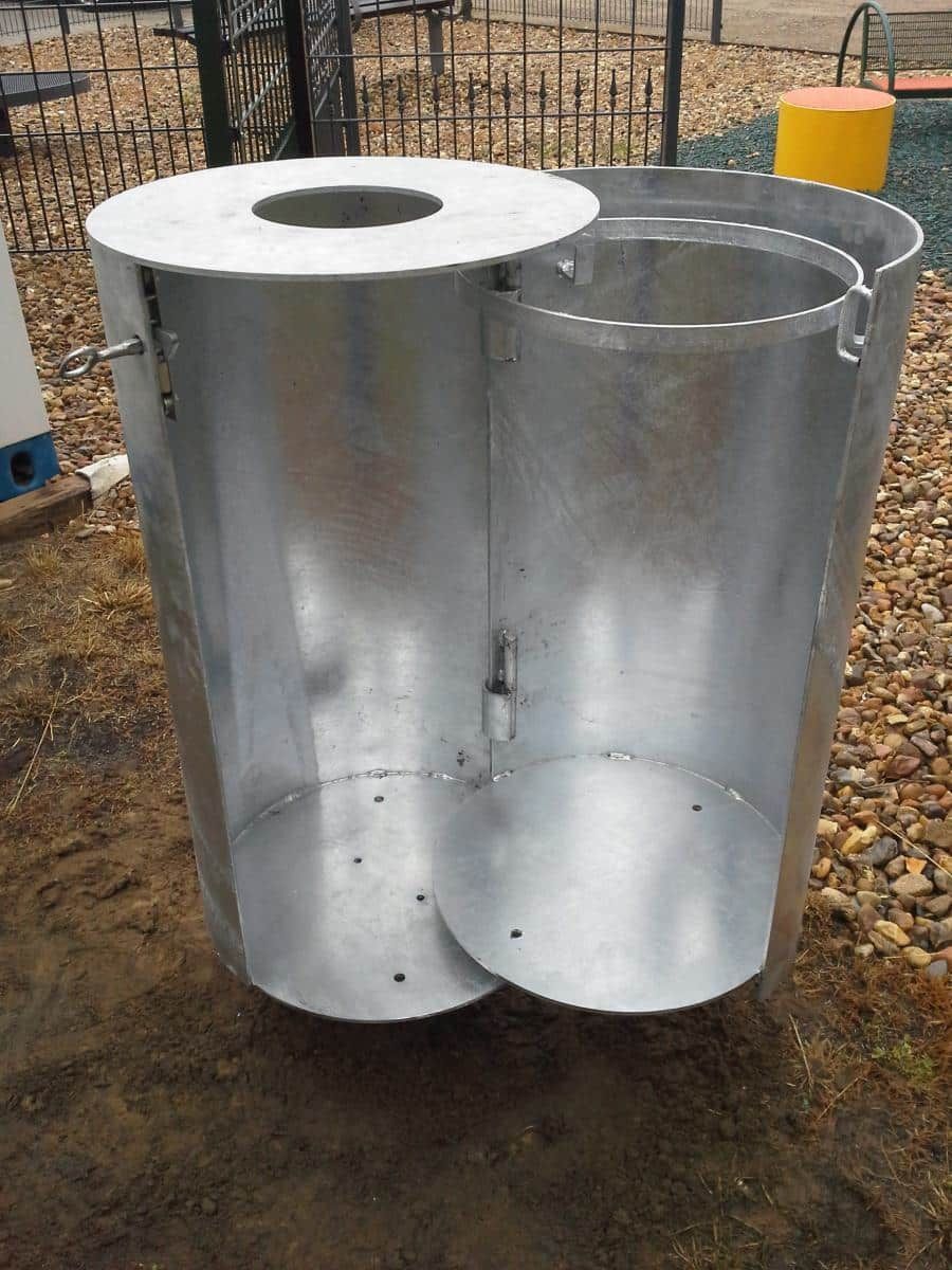 Zwei große, verzinkte Metallzylinder mit Aussparungen stehen im Freien auf Kies.