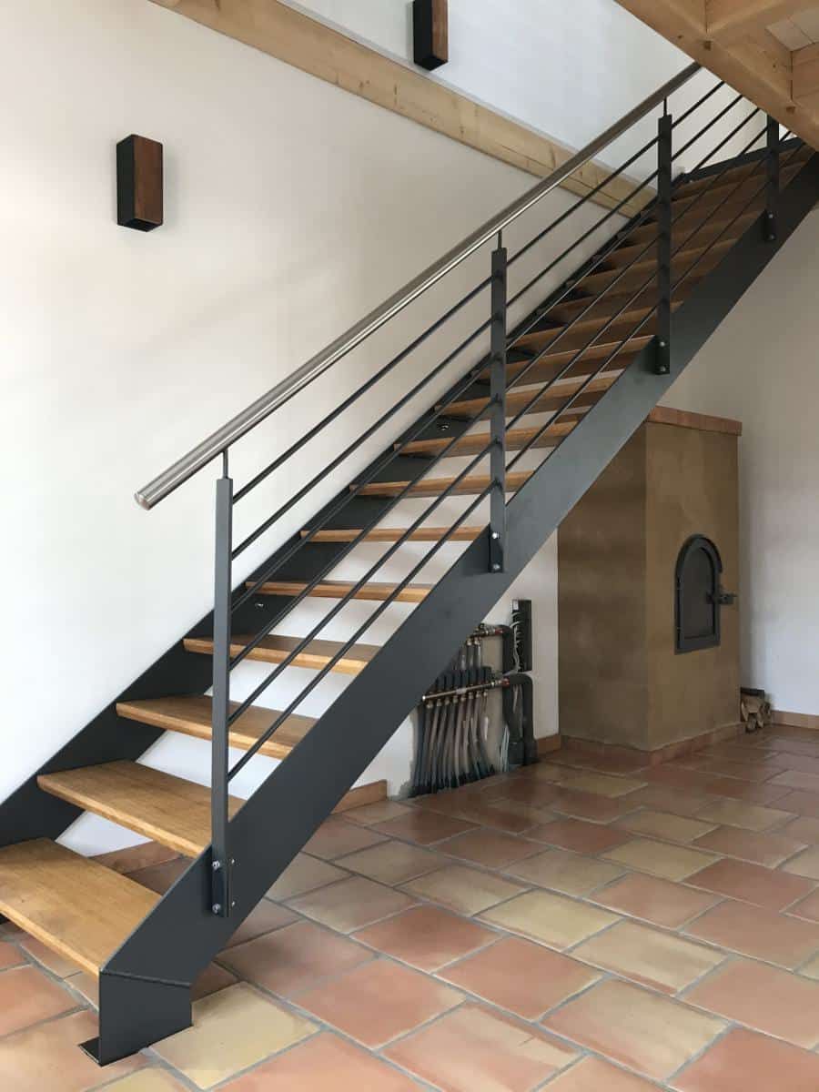 Innentreppe mit Metallgeländer und Holzstufen über Terrakottafliesenboden.