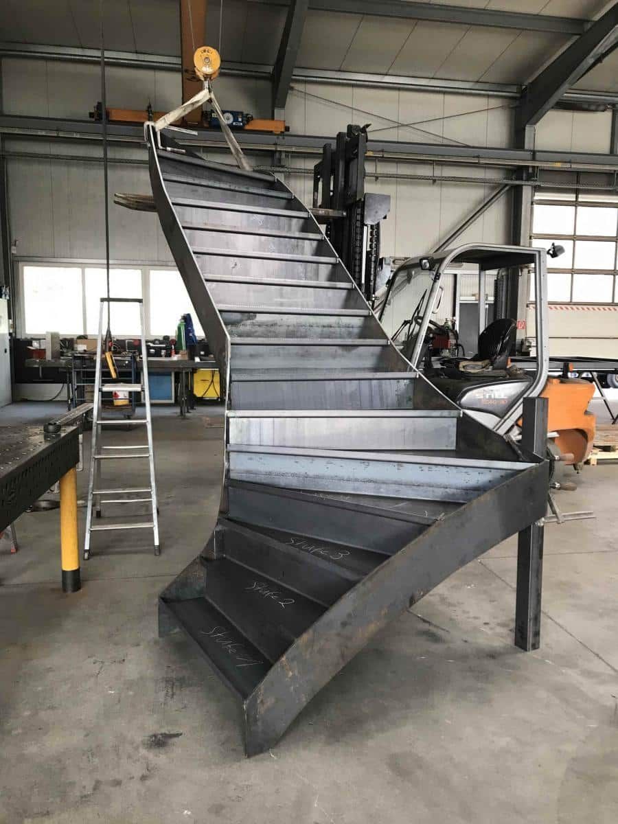 Große industrielle Metalltreppe mit gebogenem Fuß in einer Lagerhalle.