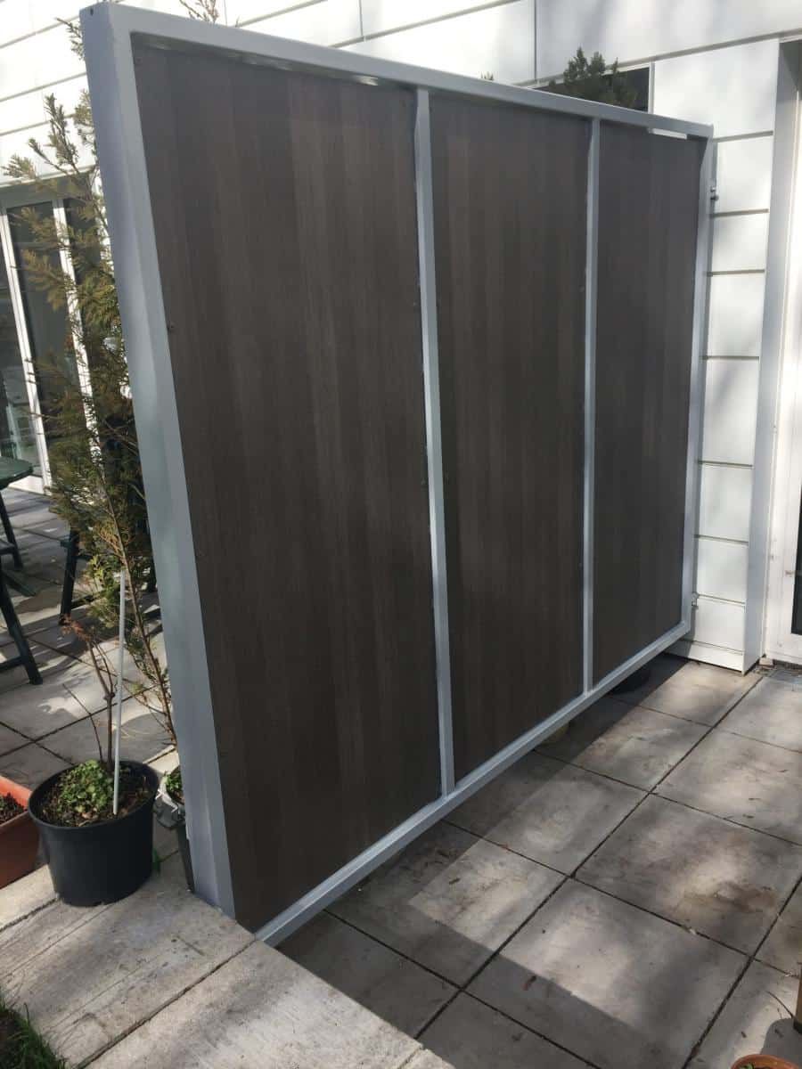 Großer grauer Sichtschutz oder Sichtschutzpaneel für den Außenbereich auf einer Terrasse neben einer weißen Hauswand