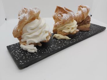 Tres pasteles con crema batida y azúcar glas en una bandeja negra