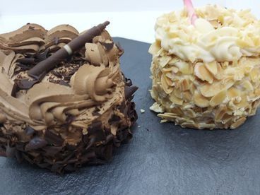 Un pastel de chocolate y un pastel blanco están sobre una mesa.