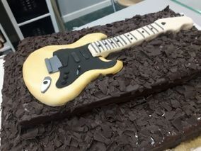 Un pastel de chocolate con una guitarra encima.