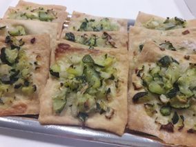 Una bandeja de pizza con verduras encima está sobre una mesa.