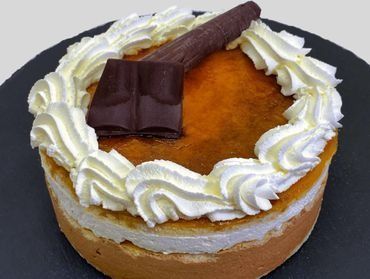 Un pastel con crema batida y chocolate encima está sobre un plato negro.