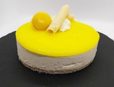 Un pequeño pastel con glaseado amarillo encima está sobre un plato negro.