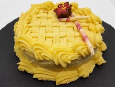 Un pastel con glaseado amarillo y una flor encima.