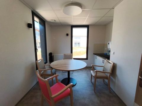 Petite salle de réunion avec une table ronde, quatre chaises et un écran de télévision près de la fenêtre.