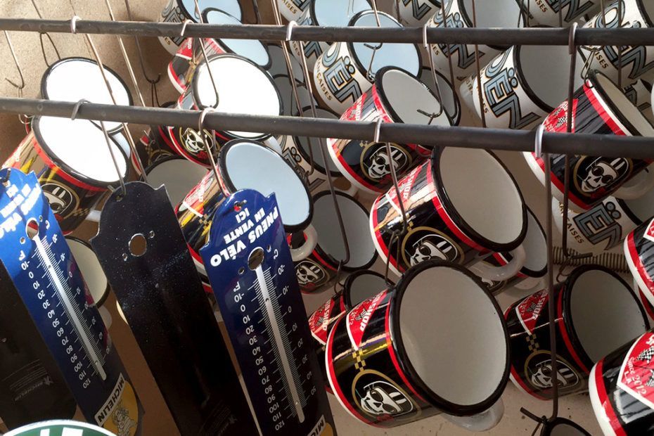 Des rangées de tasses décoratives rouges, noires et blanches sont présentées avec des thermomètres contre un mur.