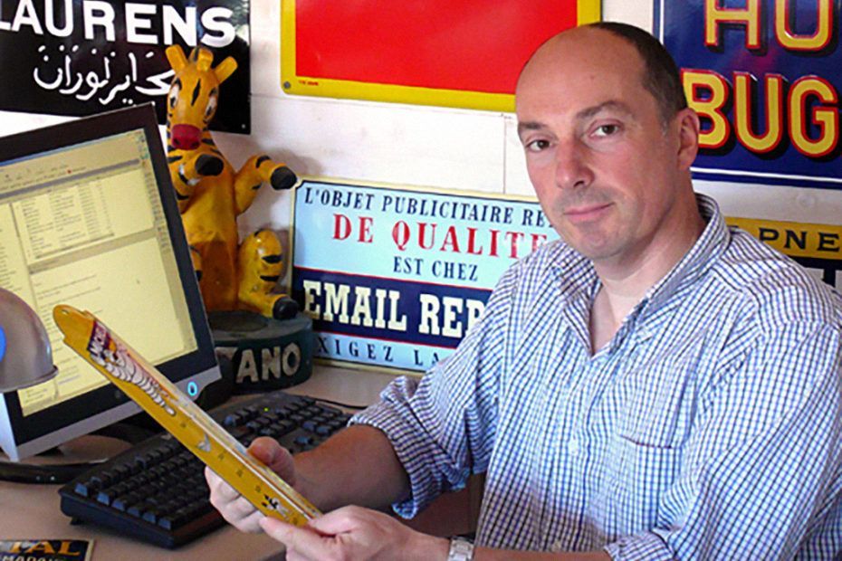 Un homme en fonction, tenant une règle, entouré de panneaux.