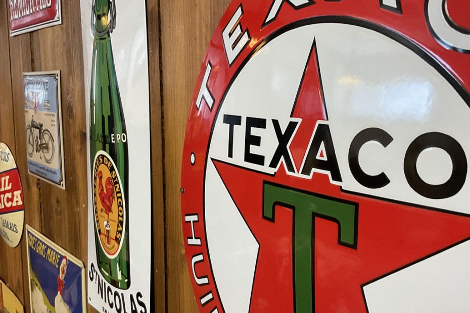 Gros plan sur une enseigne Texaco vintage et d'autres décorations murales colorées.