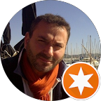 Homme barbu portant une écharpe orange, regardant l'objectif, arrière-plan portuaire, insigne orange.