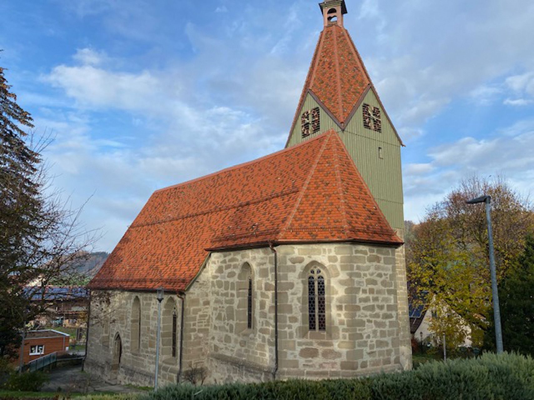 Eine kleine Kirche mit einem roten Ziegeldach und einem Glockenturm.