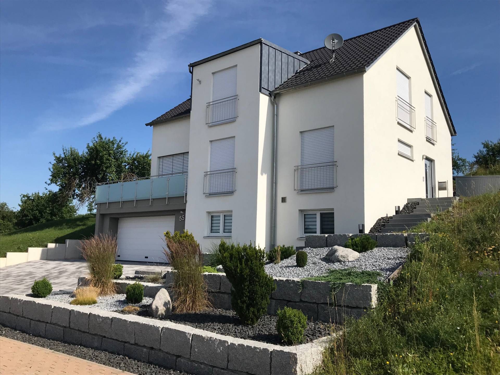 Weißes Haus mit einer Backsteinmauer davor