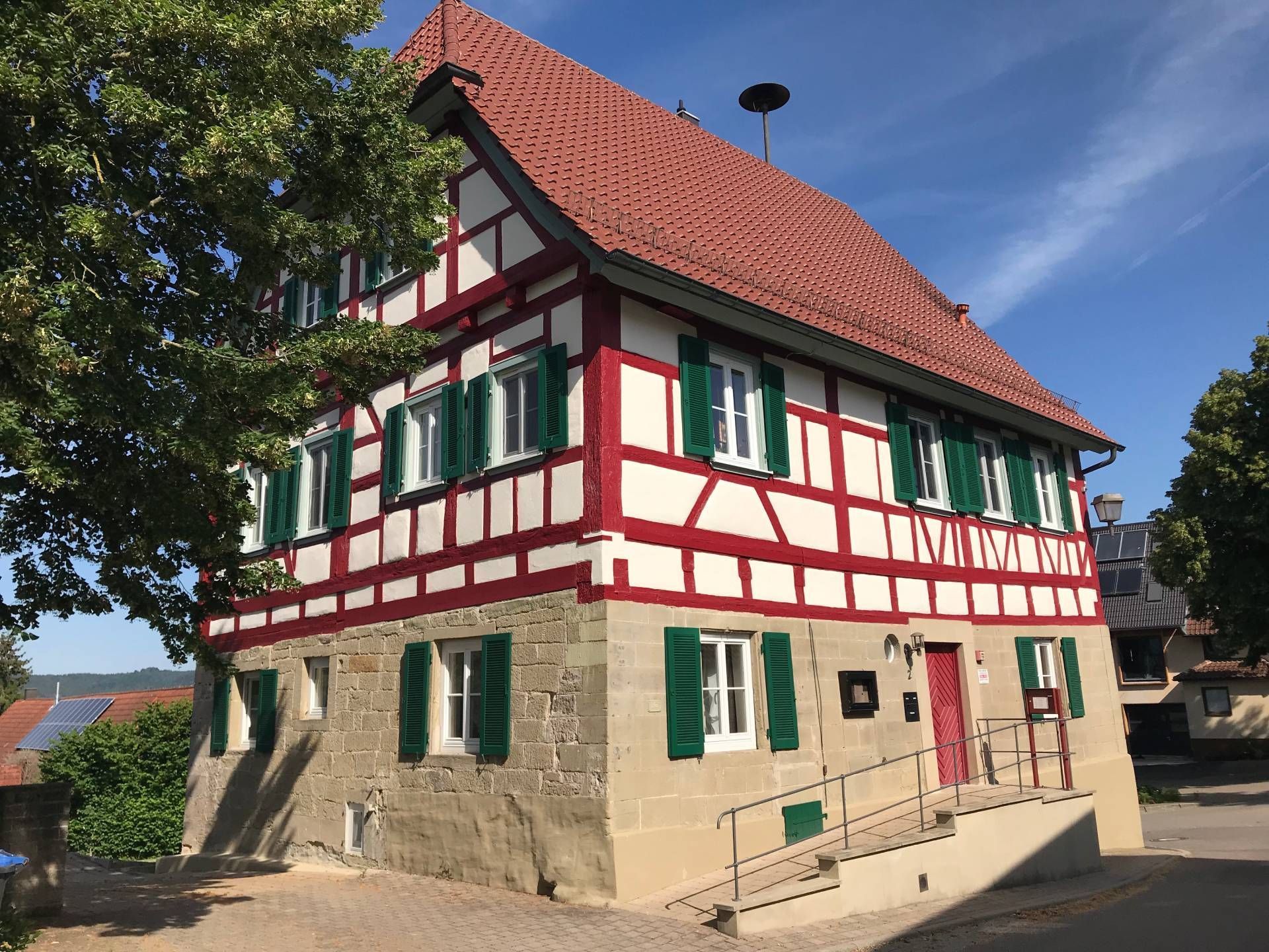 Ein großes Haus mit rotem Dach und grünen Fensterläden