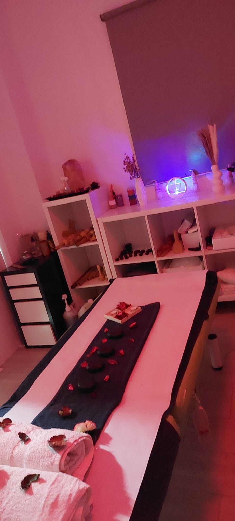 Una mesa de masajes en una habitación rosa con toallas encima.