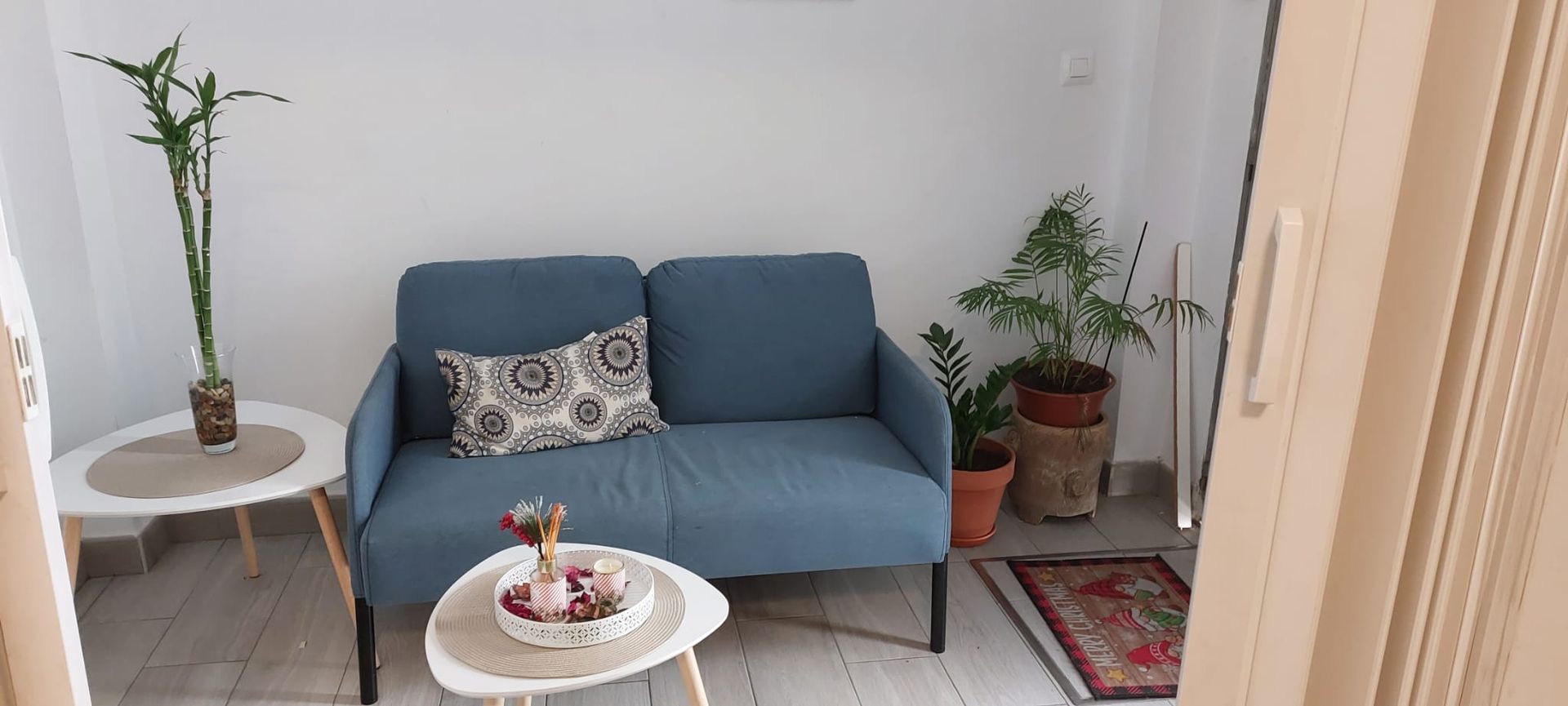 Una sala de estar con un sofá azul y dos mesas.