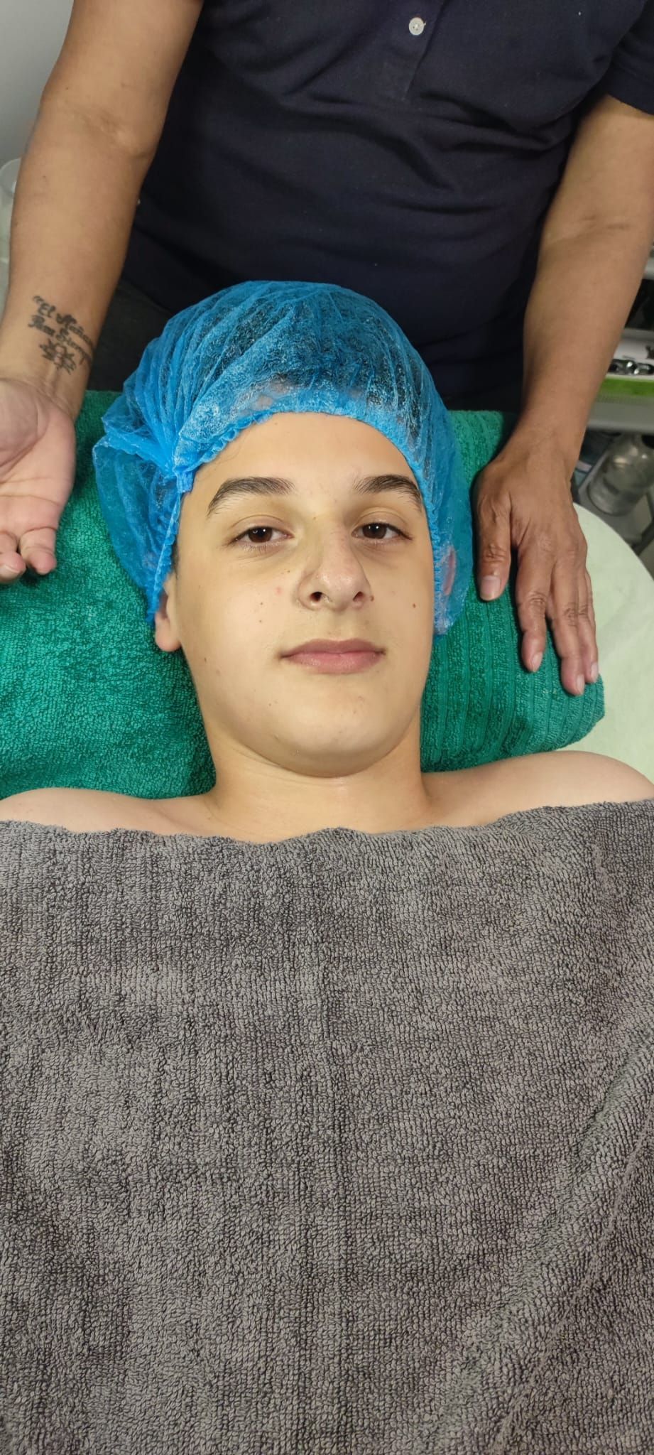 Un niño pequeño está acostado en una mesa recibiendo un masaje.