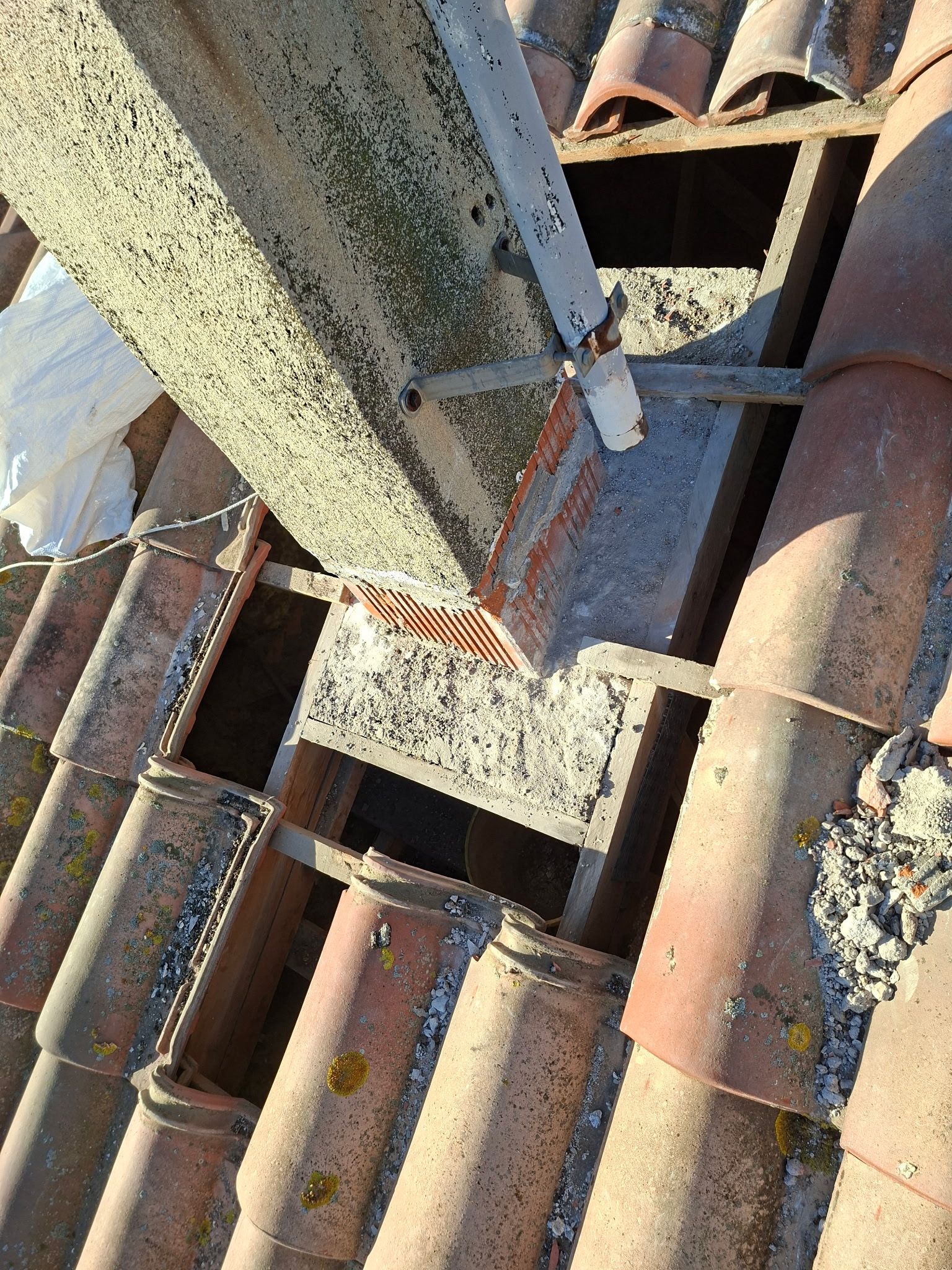 Maison avec toiture en cours de rénovation ; ouvriers sur le toit et les échafaudages, débris au sol.