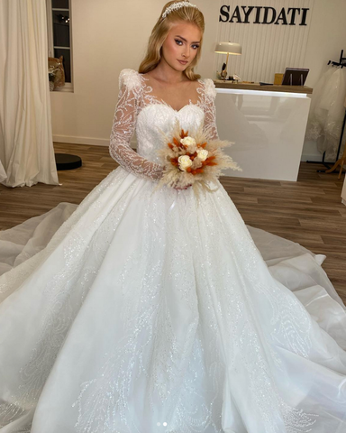 Une femme en robe de mariée blanche tient un bouquet de fleurs.