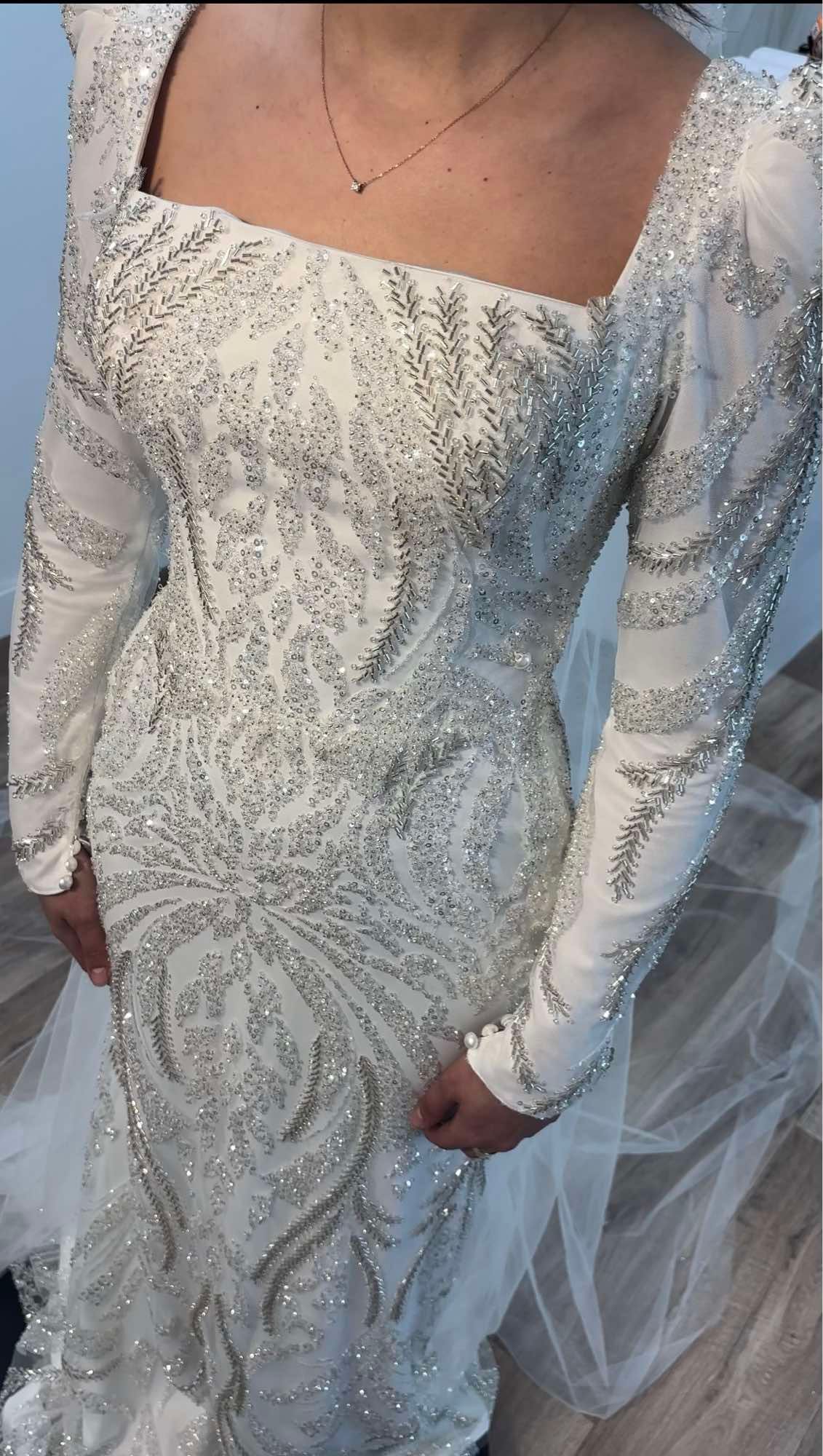 Une femme porte une robe blanche à manches longues et un collier.