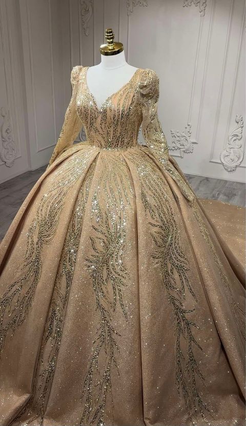 Une robe de bal dorée à manches longues est sur un mannequin.