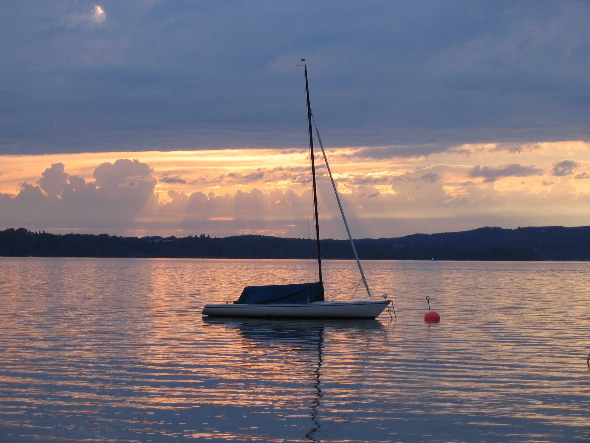 Starnberger See im Sonnenuntergang mit Segelboot in der Mitte