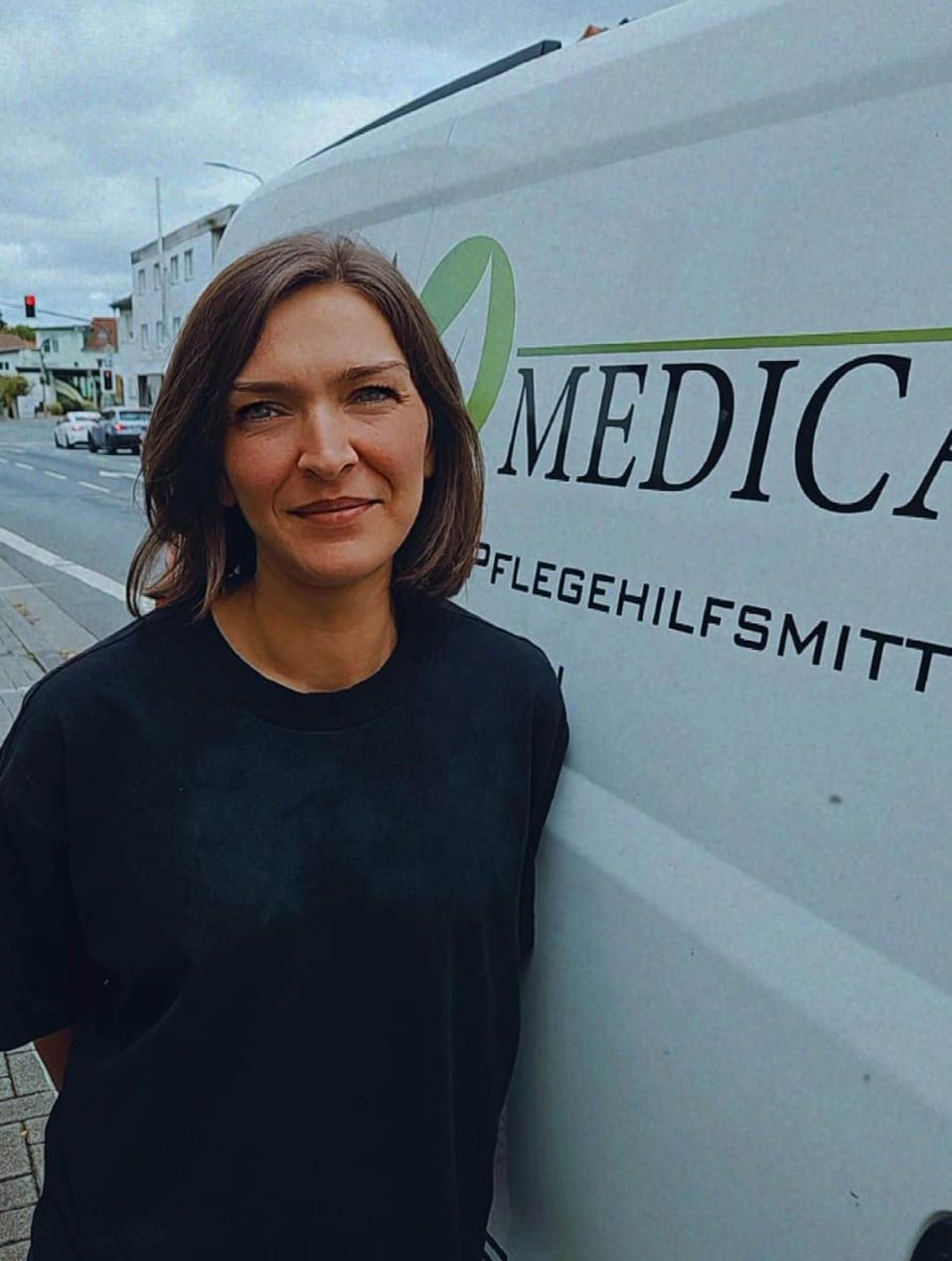 Eine Frau steht auf der Straße neben einem Lieferwagen mit dem Logo „Medica“.